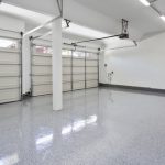 Empty two-car garage interior with clean, shiny epoxy flooring and two closed metal roll-up doors.