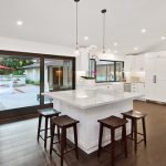 A kitchen with white counters and wooden floors