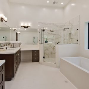 Modern bathroom with a glass shower enclosure, freestanding tub, double vanity, and white marble accents.