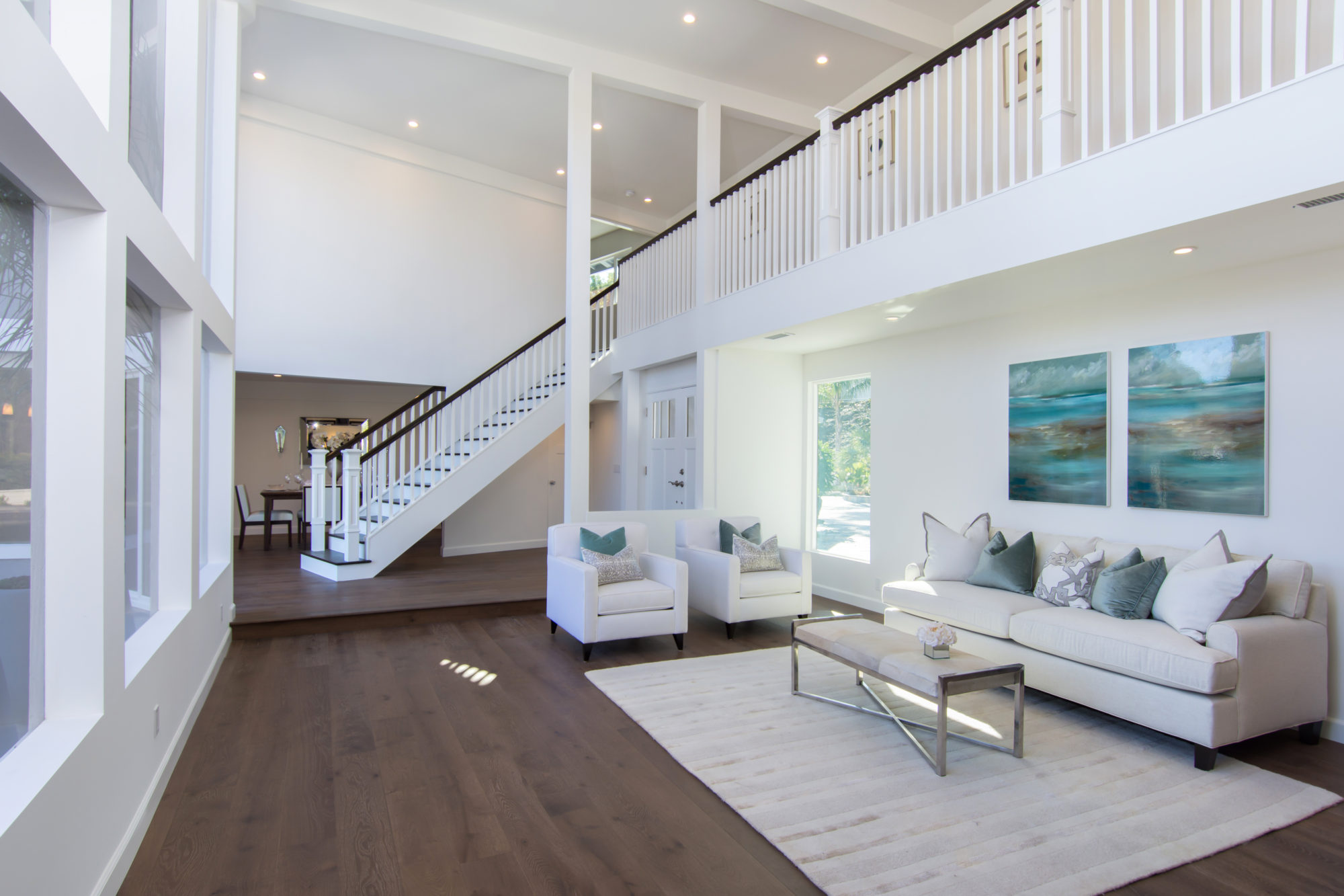 A living room with stairs and white furniture.