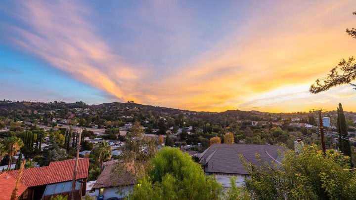 Sunset over a suburban neighborhood with colorful sky and hills.