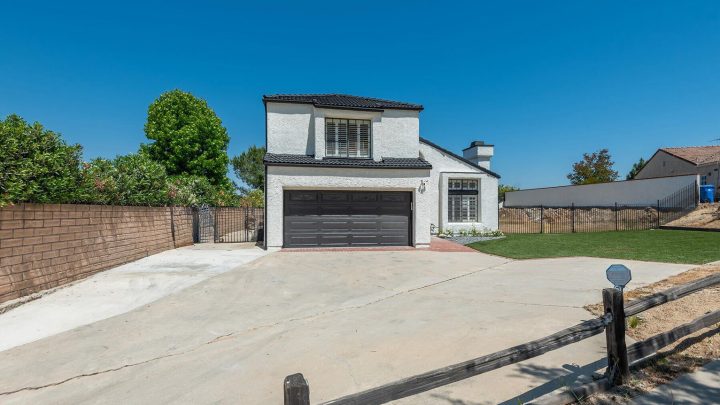 Modern two-story house with a large driveway and garage under a clear blue sky.