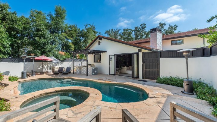Modern backyard with a kidney-shaped pool and patio seating area.
